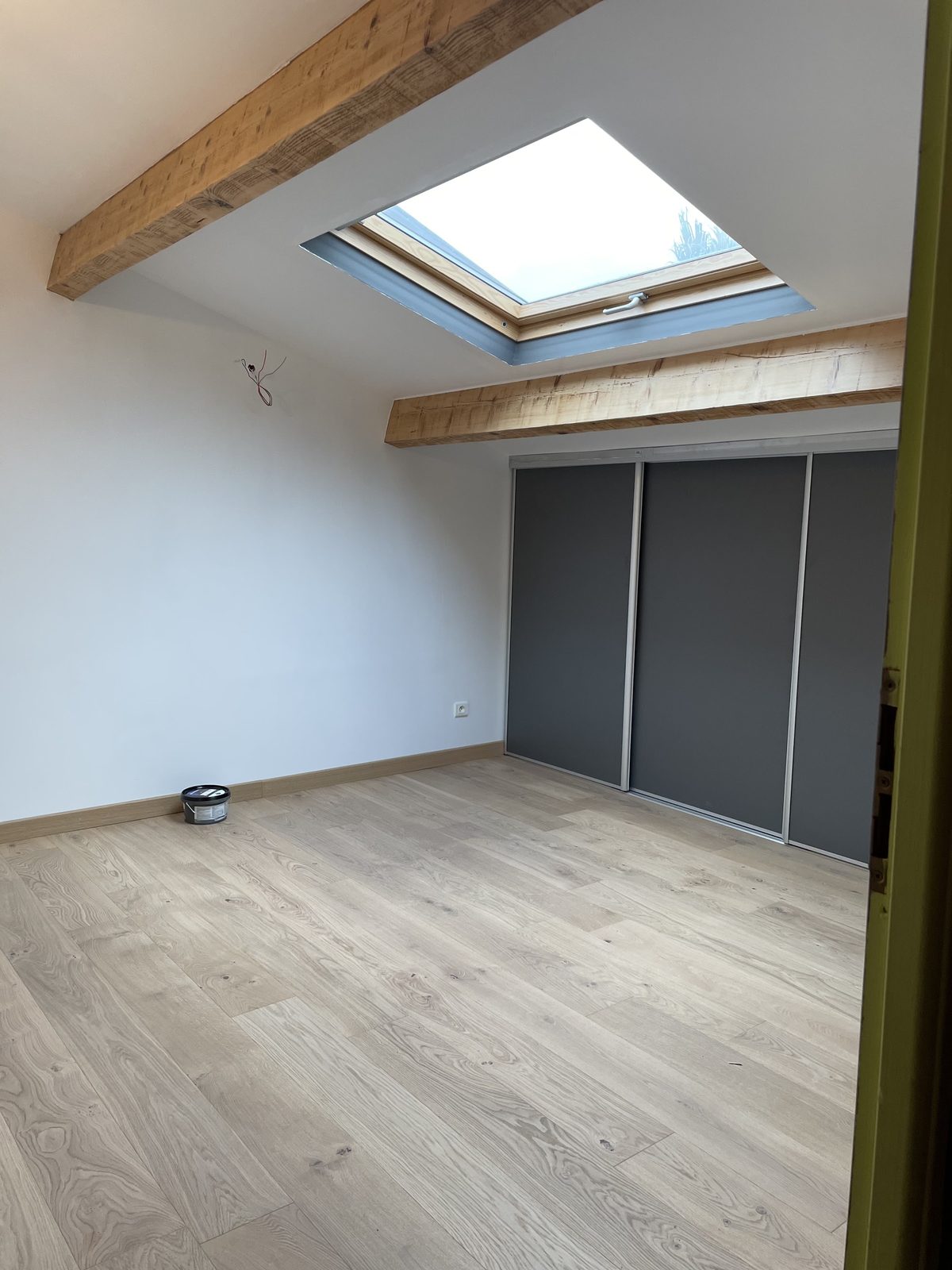 Chambre rénovée avec parquet et poutre apparente